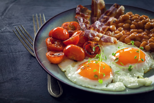 Fried eggs, bacon, beans and cherry tomatoes  