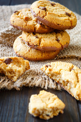 Chocolate whole cookies and pieces with crumbs on burlap on rustic wood table
