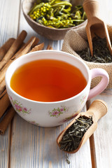 Cup of tea and dried tea leaves on wooden planks