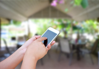 hand hold and touch screen smart phone, on blurred photo of coff