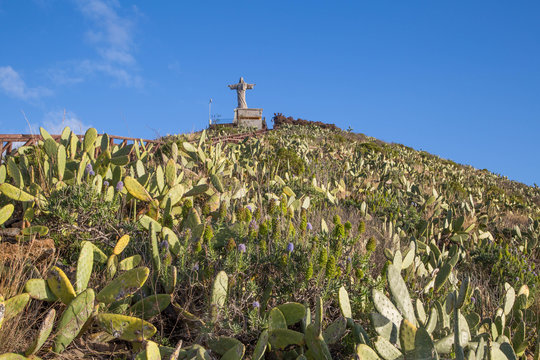 Christusstatue auf mit Kakteen bewachsenem Felsvorsprung Cristo Rei auf Madeira und h&ouml;lzerne Treppe auf den Felsvorsprung
