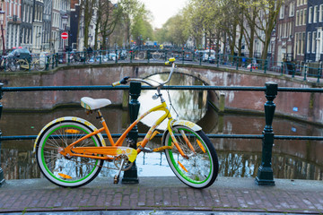 Obraz premium Orange bicycle next to canal of Amsterdam 