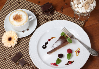Piece of chocolate cake with cup of cappuccino.