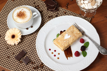 Fototapeta na wymiar Piece of napoleon cake with cup of cappuccino.