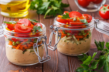 Healthy breakfast - hummus with vegetables in glass jars.