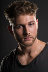 Portrait of handsome young bodybuilder in black tee shirt, on grey