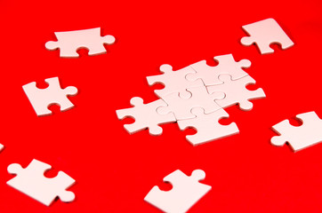 solving the puzzle, still life with a white jigsaw/puzzle incomplete over a red background, symbol of problem solving