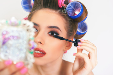 Young girl doing makeup and hairstyle using curlers