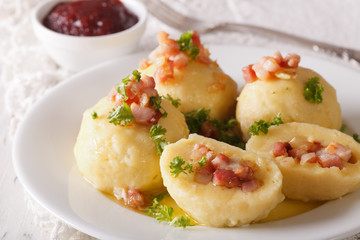 potato dumplings with bacon close-up and lingonberry sauce. horizontal
