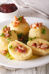 Potato dumplings stuffed with ham and onion close-up and lingonberry sauce. Vertical
