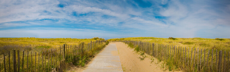 Summer holiday panoramic sea beach background. Path to the beach with beautiful sky and grass.