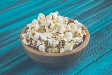 Popcorn in wooden plate on a blue background