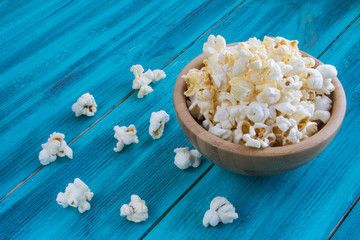 Popcorn in wooden plate on a blue background