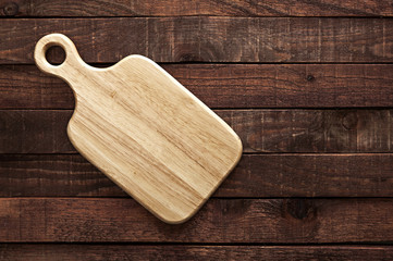 Cutting board on dark old wooden table. Top view