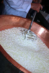 cheesemaker stirs the curds into the big copper cauldron