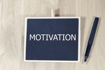 sentence motivation written with chalk on a blackboard, on a table with pen