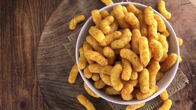 Rotating Peanut Puffs (seamless loopable; 4K footage) on wooden background