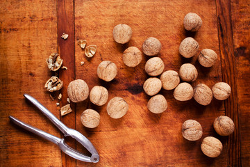 Fototapeta na wymiar Walnuts with nutcracker on wooden background, selective focus