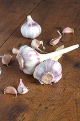Still life with garlic heads and garlic cloves on brown wooden background vertical photo closeup