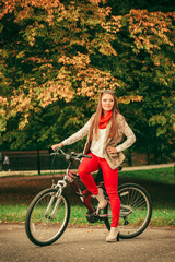 Fototapeta premium girl relaxing in autumnal park with bicycle.