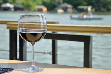 Glass of red vine by the river on pleasant spring day