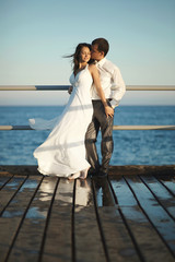 Gorgeous wedding couple standing on pier under spray, splashes a