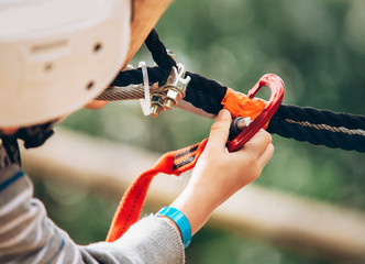 Child hand with safety spring hook in the rope park attraction