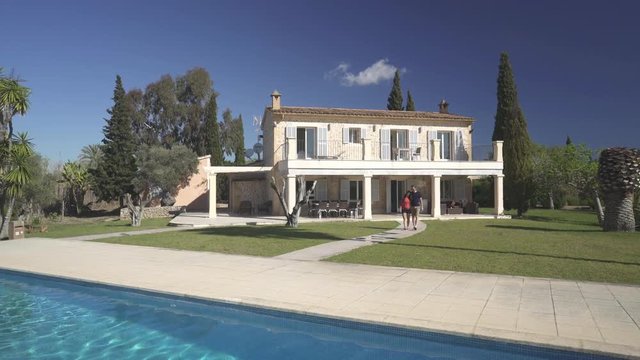 4k footage, young couple waling on their huge country property with stone finca and swimming pool
