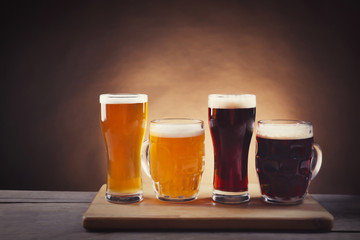 Different sorts of draft beer in glasses on wooden table. Retro stylization