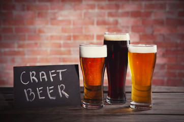 Glasses with different sorts of craft beer on brick wall background. Retro stylization