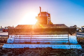 Sunset above the bulldozer working on the construction site © Stockr