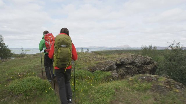 People hiking in nature living active lifestyle. Couple hikers on travel walking with hiking poles in beautiful landscape. Lake Myvatn, north Iceland. RED EPIC, STEADICAM.