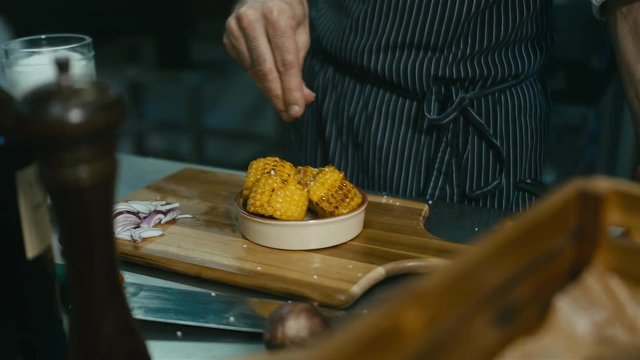Chef sprinkling corn with salt. 60 FPS slow motion shot. Blackmagic URSA Mini