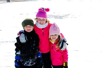 Three happy siblings in the snow on vacation.