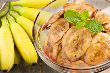 A banch of bananas and a sliced banana on chopping wood on wood