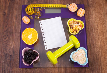 Digital scale with tape measure, tablets, dumbbells, fruits, muesli, slimming concept