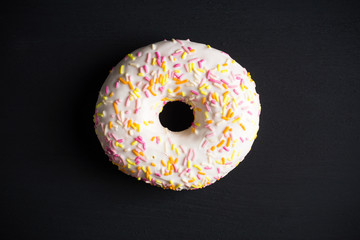 Donut with sprinkles on the black background