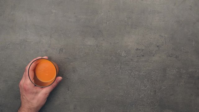 Preparation of fresh carrot juice on grey kitchen table. Top view stop motion animation.