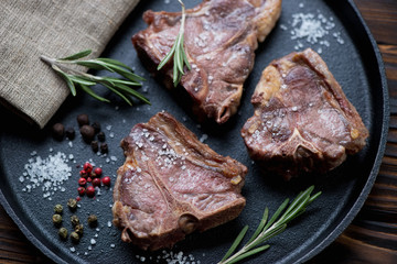 Frying pan with grilled T-bone lamb steaks, closeup, studio shot