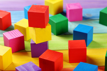 Colorful wooden toy cubes on a colorful wooden background