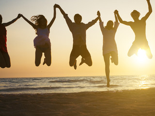group of people jumping at beach. Backlight shot.