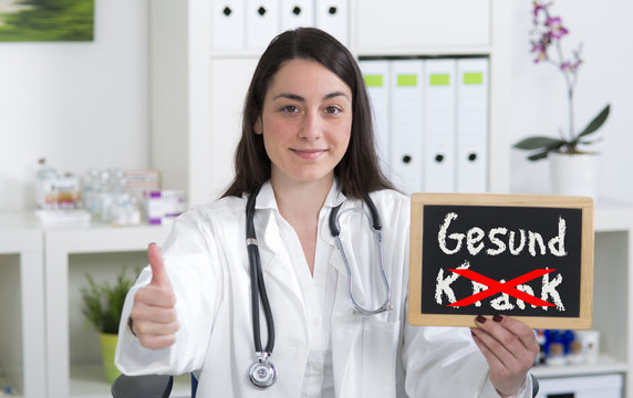 &Auml;rztin h&auml;lt Hinweistafel mit