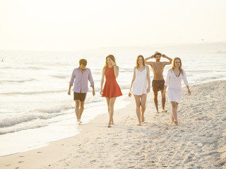 group of friends walking on the beach at sunse