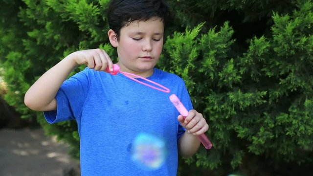 Portrait of a cute little boy is blowing a soap bubbles