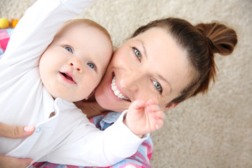 Young mother taking a selfie with her baby on the floor, close up - Powered by Adobe