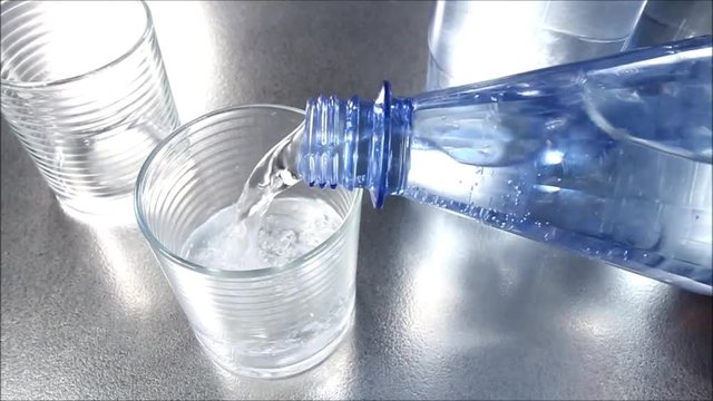 Mineralwasser aus Flasche wird eingeschenkt, Zeitlupe