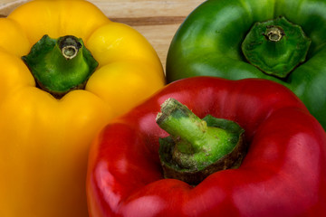 Red Green and Yellow Capsicums on a Wooden Table