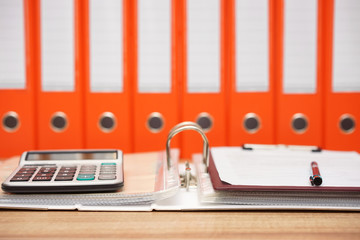 calculator and document on top  of open folder with documentatio