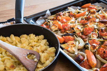 Roasted vegetables and cheese in a baking tray and a frying pan with swabian noodles