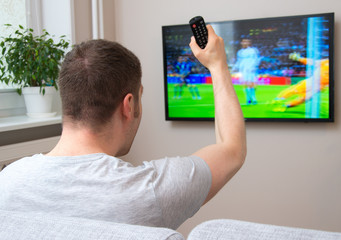 Goal! Man watching football match on television at home.